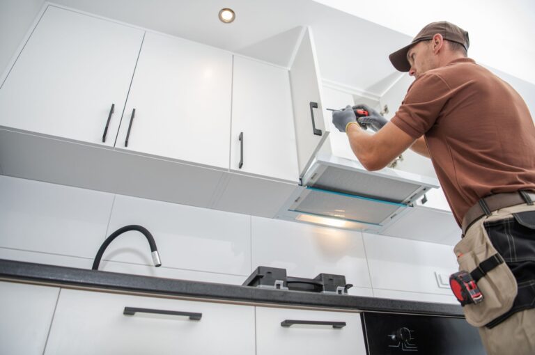 A handyman installing or repairing a kitchen cabinet above a stove in a modern white kitchen , cabinets with new handles , unique cabinet handle designs,affordable cabinet handle replacements